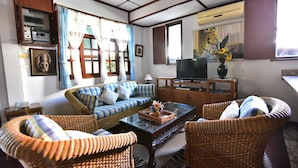 A living room with wicker furniture, a sofa, a coffee table, and a television. - Nong Apartment Pattaya - Adults Only (Pattaya)