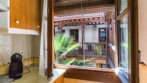 A kitchen with wooden cabinets, a coffee maker, and a view of a balcony with plants. - La casa de los Infantes by Toledo AP (Toledo)
