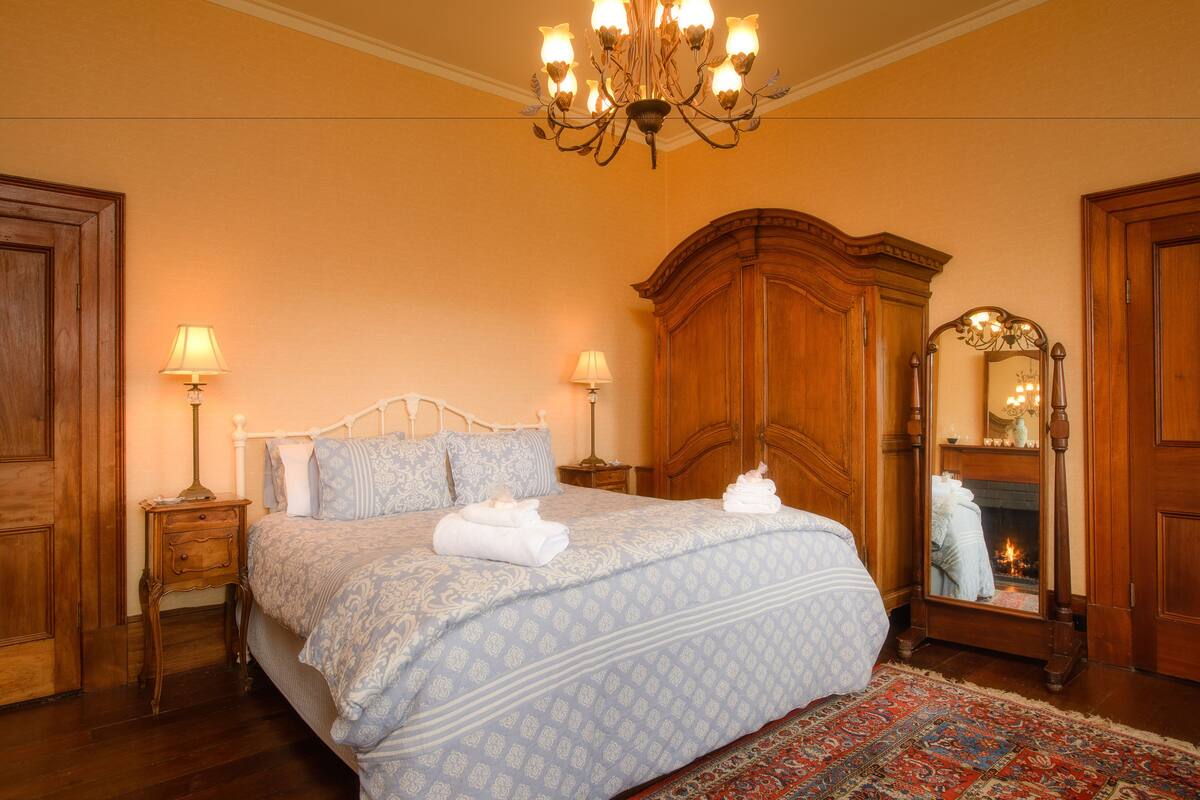 Un dormitorio con una cama grande, armario de madera y un espejo.