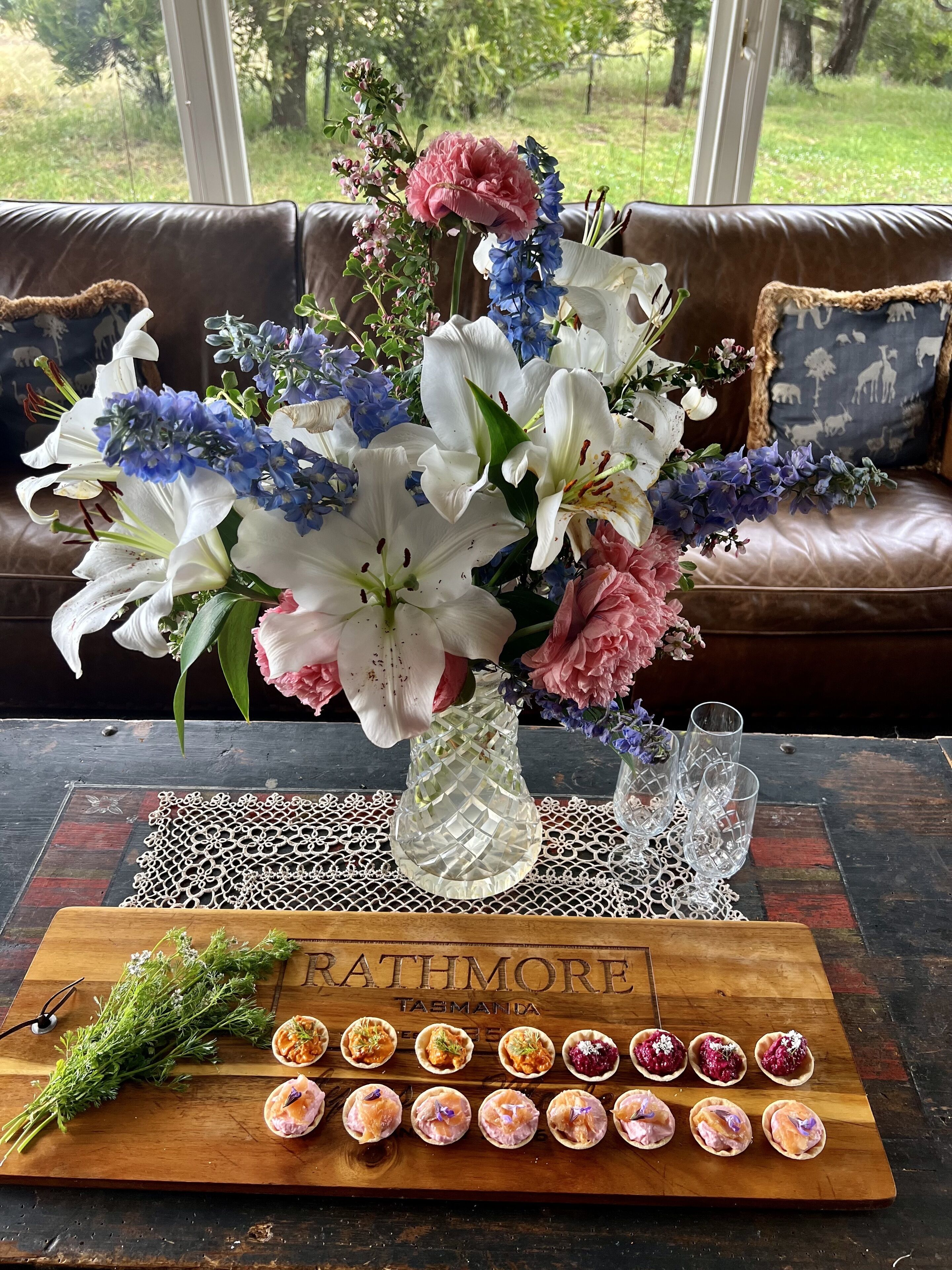 A dining table with a floral centerpiece and a tray of appetizers.