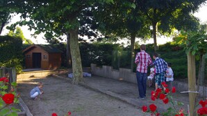 Un jardin agrémenté d’une structure en bois, d’une zone délimitée par une clôture et de rosiers rouges.
