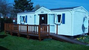 Une maison mobile de plain-pied, dotée d’un porche à l’avant et d’une antenne parabolique.
