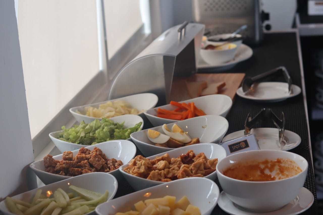 A buffet with various food items including salads, meats, and a bowl of soup.