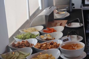 A buffet with various food items including salads, meats, and a bowl of soup.