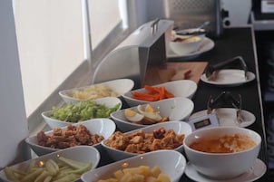Un bufé con diversos alimentos, incluyendo ensaladas, carnes y un tazón de sopa.