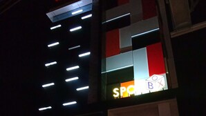 A building with a prominent 'FRONTONE' sign, a 'SPOT' sign, and a 'NOW OPEN' sign indicating a new rate. - Front One Inn Kediri (Ngasem)