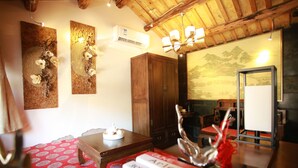 A cozy room with wooden ceiling beams, a traditional Japanese-style painting, and a bookshelf with books. - Beijing Shiguang Greatwall Boutique Inn (Yanqing)