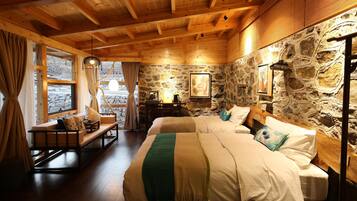 A cozy room with a stone wall, wooden ceiling, and a bed with a green throw blanket.