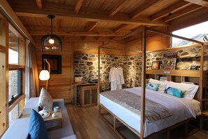 A wooden cabin room with a stone wall, a bed with a canopy, a window, and a hanging light fixture. - Beijing Shiguang Greatwall Boutique Inn (Yanqing)
