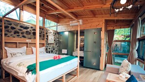 A wooden cabin bedroom with a bed, a bench, and a stone wall. - Beijing Shiguang Greatwall Boutique Inn (Yanqing)