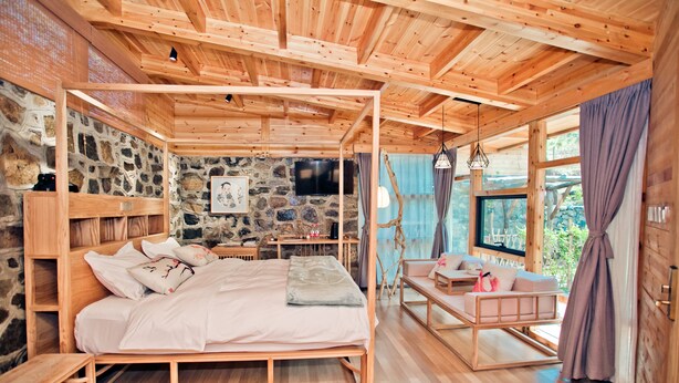 A wooden cabin interior with a bed, a small table, and a seating area. - Beijing Shiguang Greatwall Boutique Inn (Yanqing)