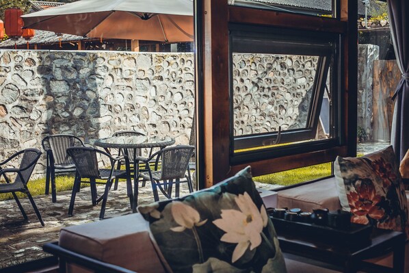 Un espace extérieur aménagé avec des murs en pierre, des chaises en osier et une table.