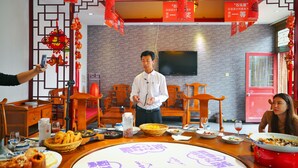 A dining area with a round table set for a meal, surrounded by wooden chairs. - Beijing Shiguang Greatwall Boutique Inn (Yanqing)