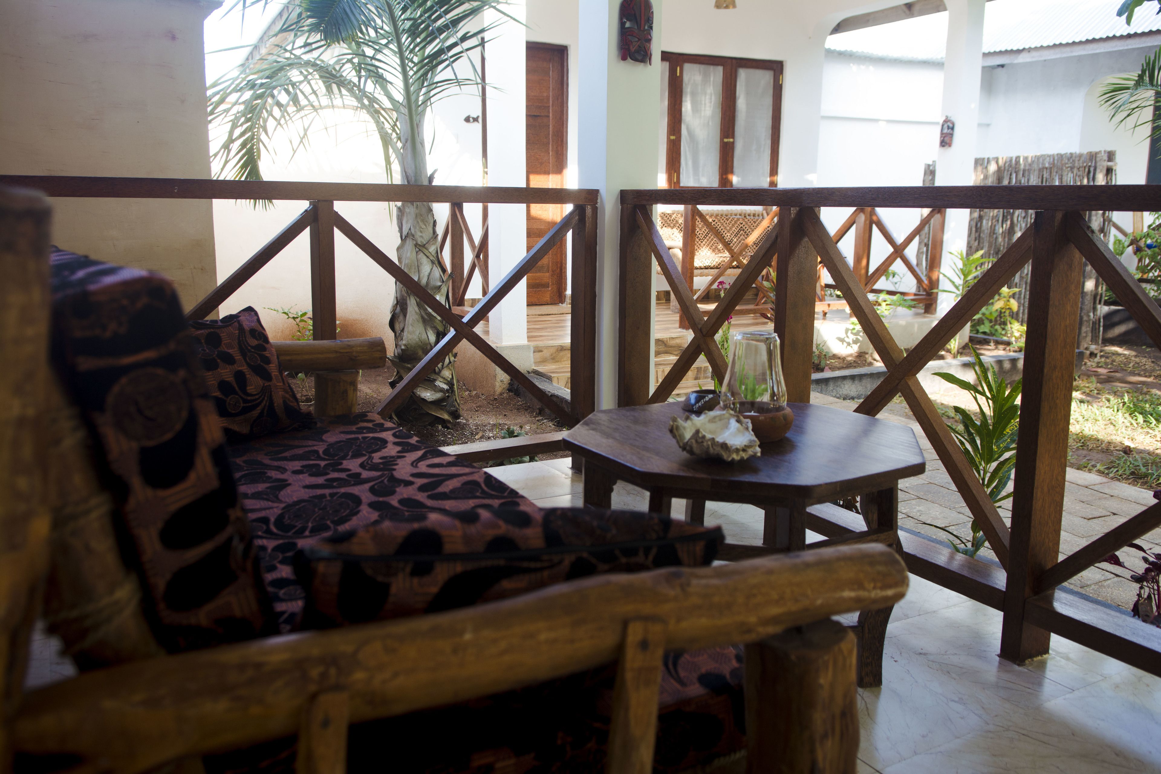 A wooden deck with a sofa and a table, surrounded by a wooden railing.