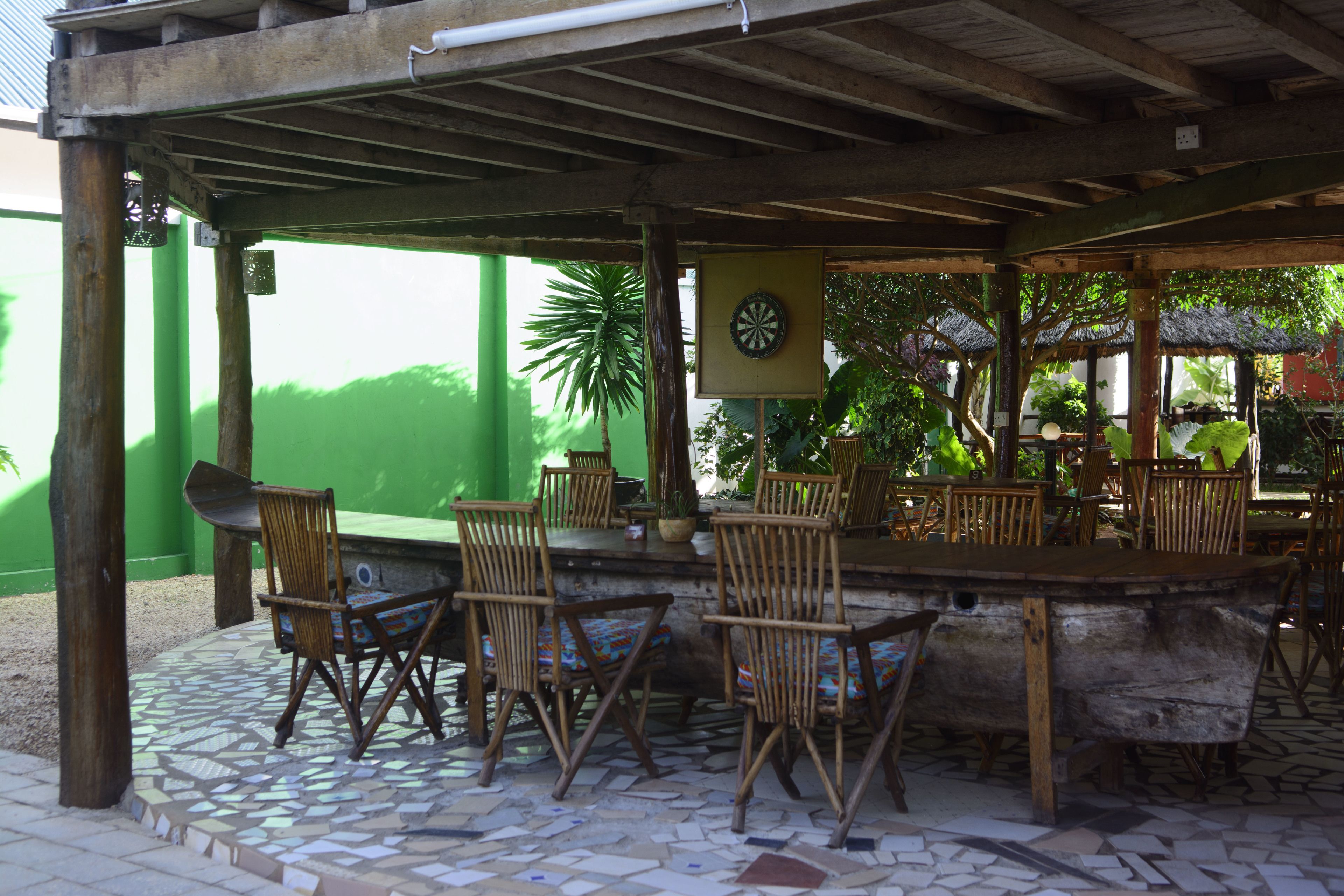 An outdoor patio with wooden chairs, a bar area, and a dartboard.