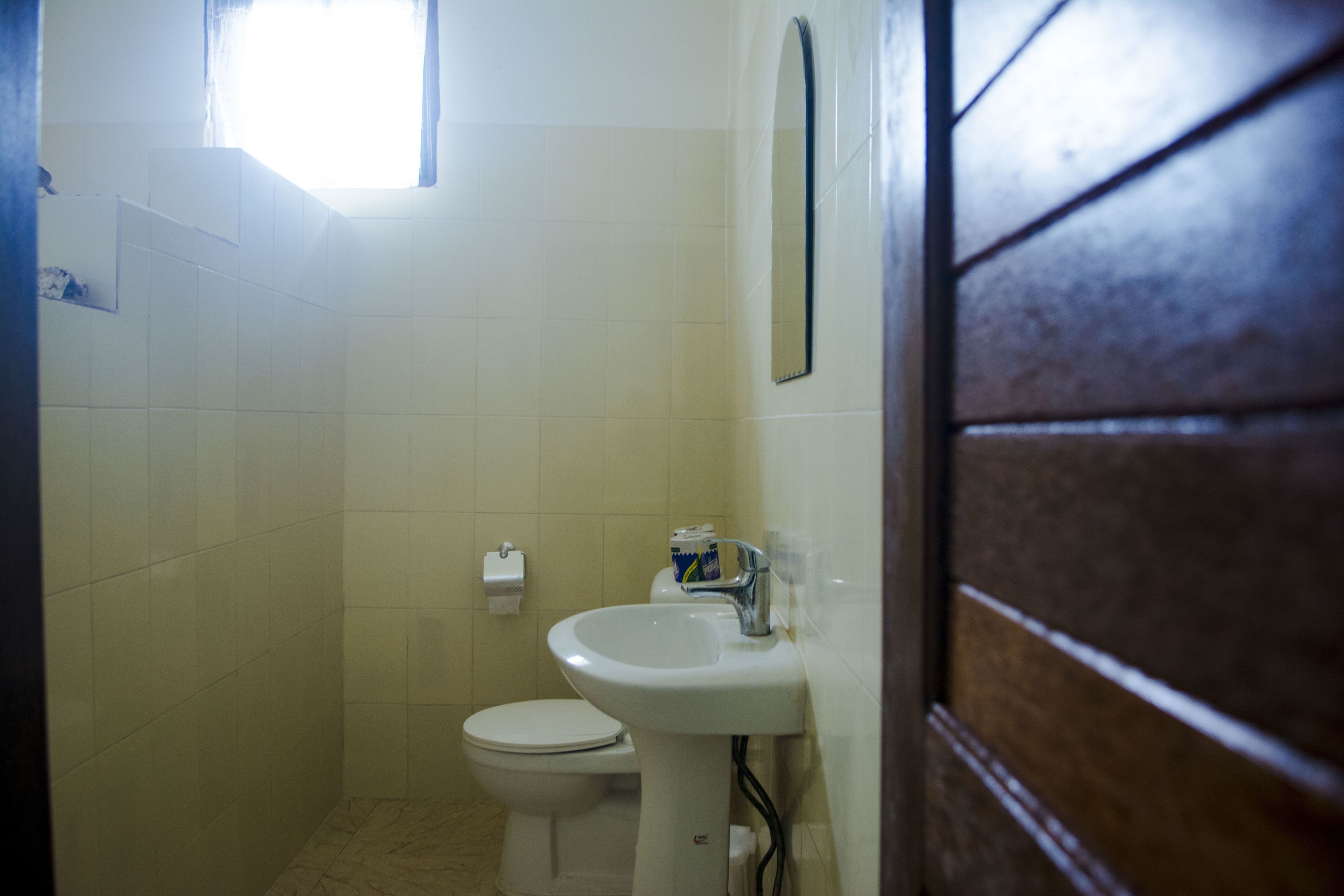 A bathroom with a toilet, sink, and a small window.