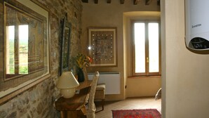 A room with stone walls, a wooden table with a lamp, a framed picture, and a radiator. - Sacreterre Room & Breakfast (Tizzano Val Parma)