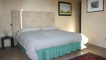 A bedroom with a bed, a nightstand, a framed picture on the wall, and a patterned rug.