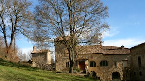 A stone building with a tiled roof, a red door, and a staircase leading to the entrance. - Sacreterre Room & Breakfast (Tizzano Val Parma)