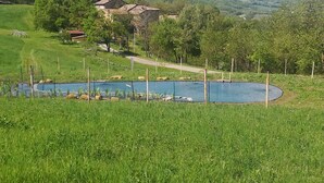 A rural landscape with a pond, a house, and rolling hills in the background. - Sacreterre Room & Breakfast (Tizzano Val Parma)