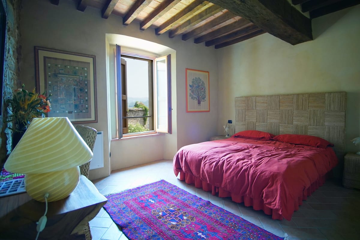 A bedroom with a bed, a window, a rug, and a lamp.