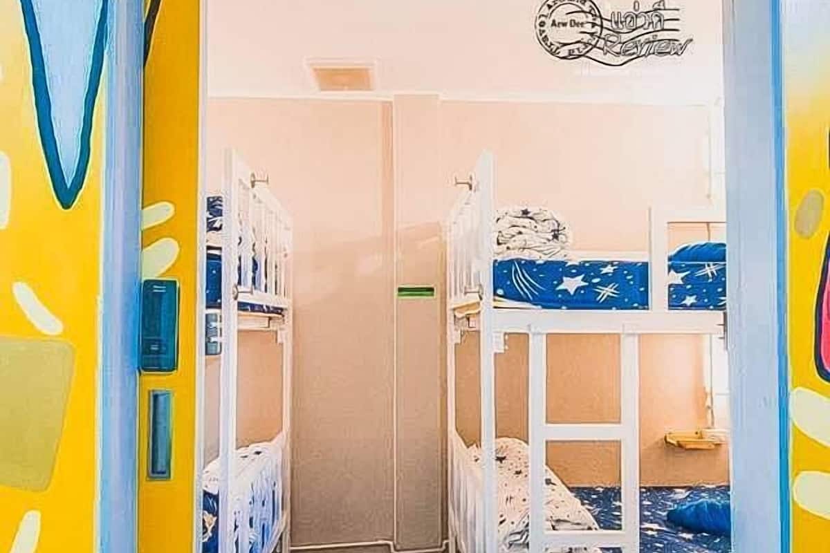 A room with bunk beds, a door with a colorful design, and a wall with a sign.