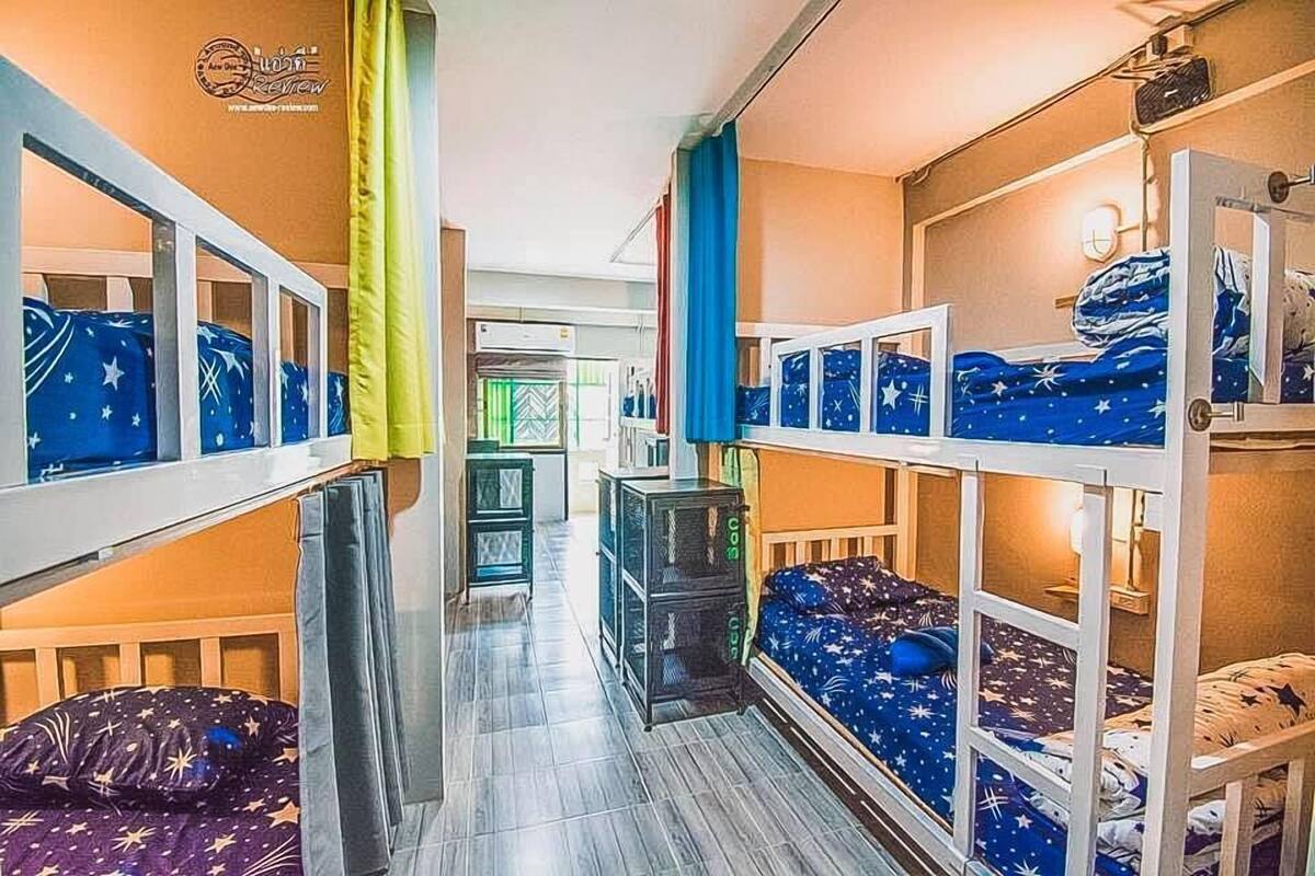 A dormitory room with bunk beds, a small desk, and a window.