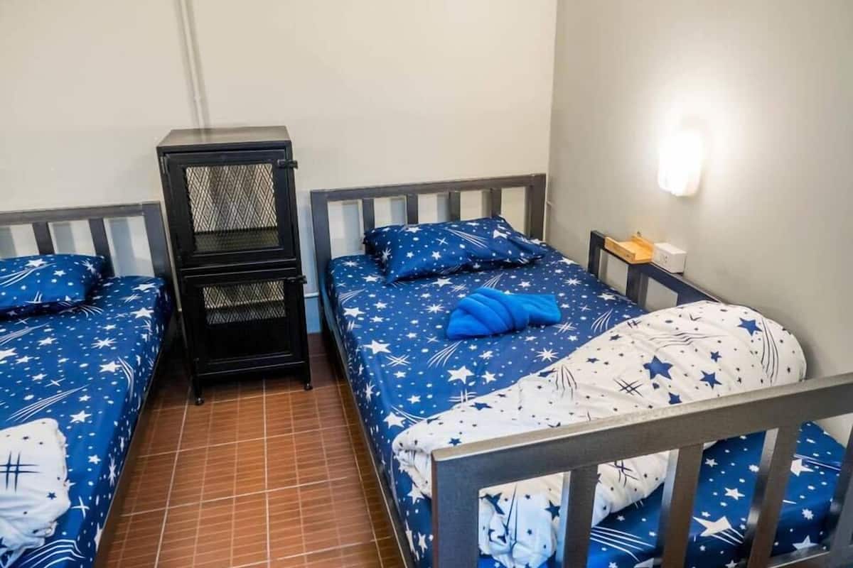 A bedroom with two beds, each with a star-patterned bedspread, a nightstand, and a wall-mounted light.