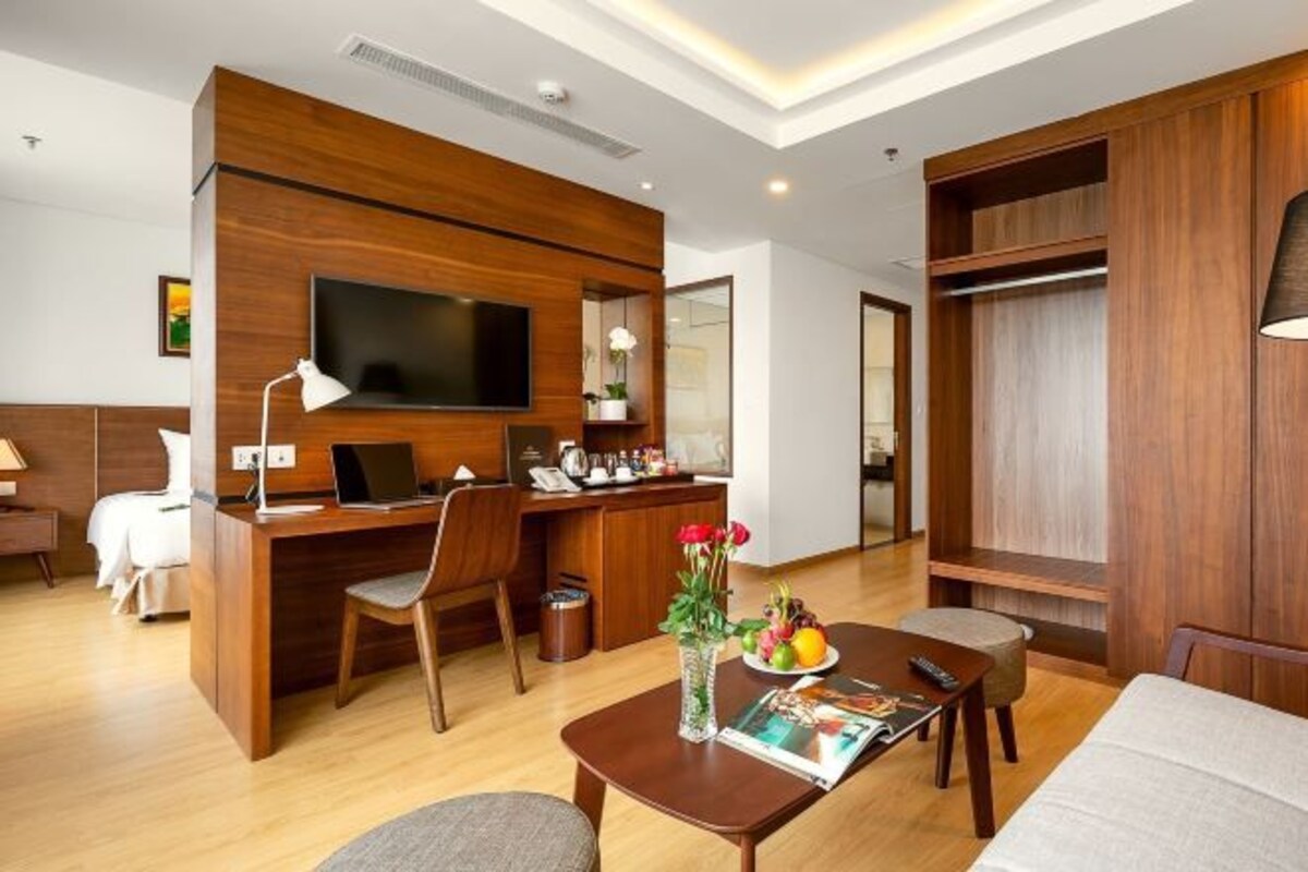 Una habitación de hotel moderna con un escritorio de madera, un televisor de pantalla plana, una cama, un sofá y una zona de comedor.