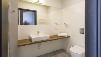 A modern bathroom with a wooden vanity, a white sink, a mirror, and a toilet.