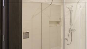 Un baño moderno con ducha de vidrio, inodoro blanco y piso de baldosas color beige.