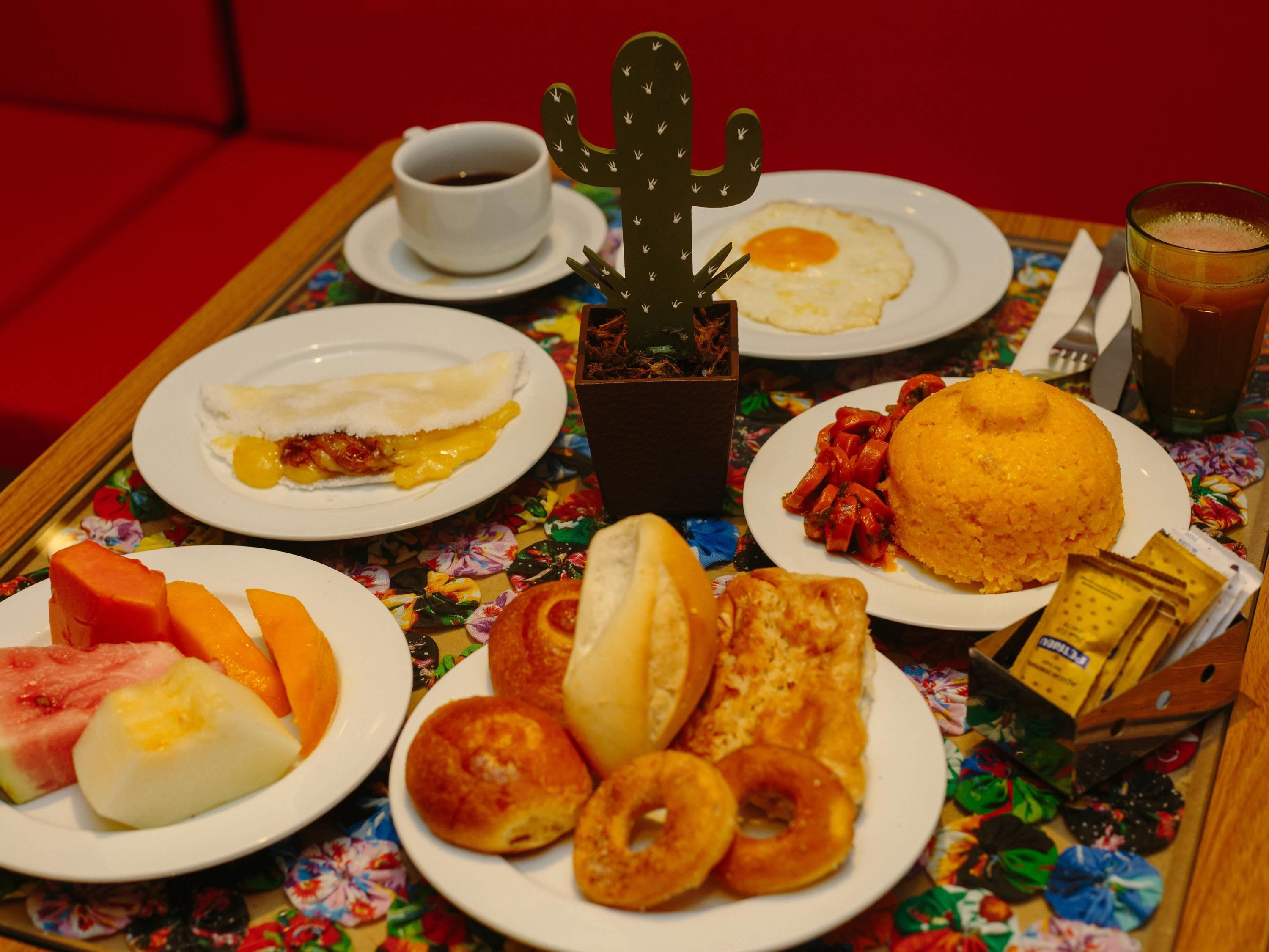 A breakfast tray with various dishes including eggs, sausage, and pastries.