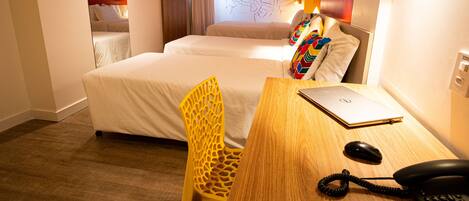 Habitación de hotel con dos camas, un escritorio de madera con una computadora portátil, un teléfono y una silla.