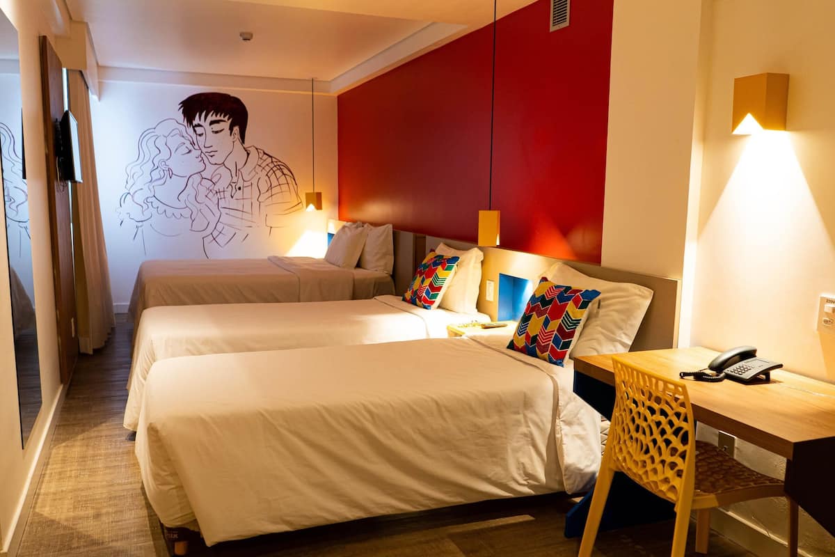 Une chambre d’hôtel avec deux lits, un bureau avec une chaise, un téléphone et un mur orné d’une fresque.
