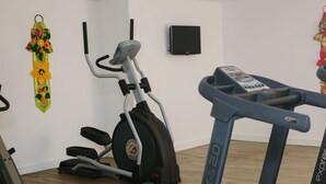 A gym with exercise equipment, a wall-mounted TV, and a decorative item.