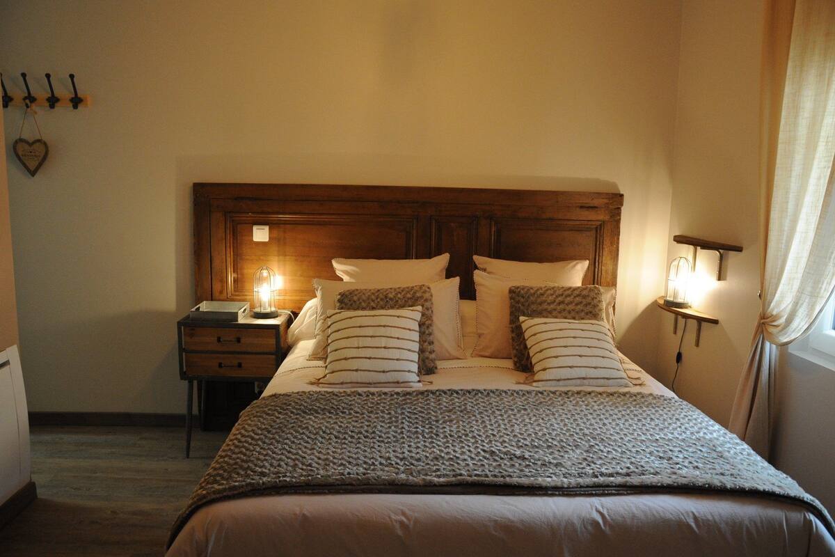 Un dormitorio con cabecera de madera, una mesita de noche con lámpara y cama con ropa de cama a rayas.