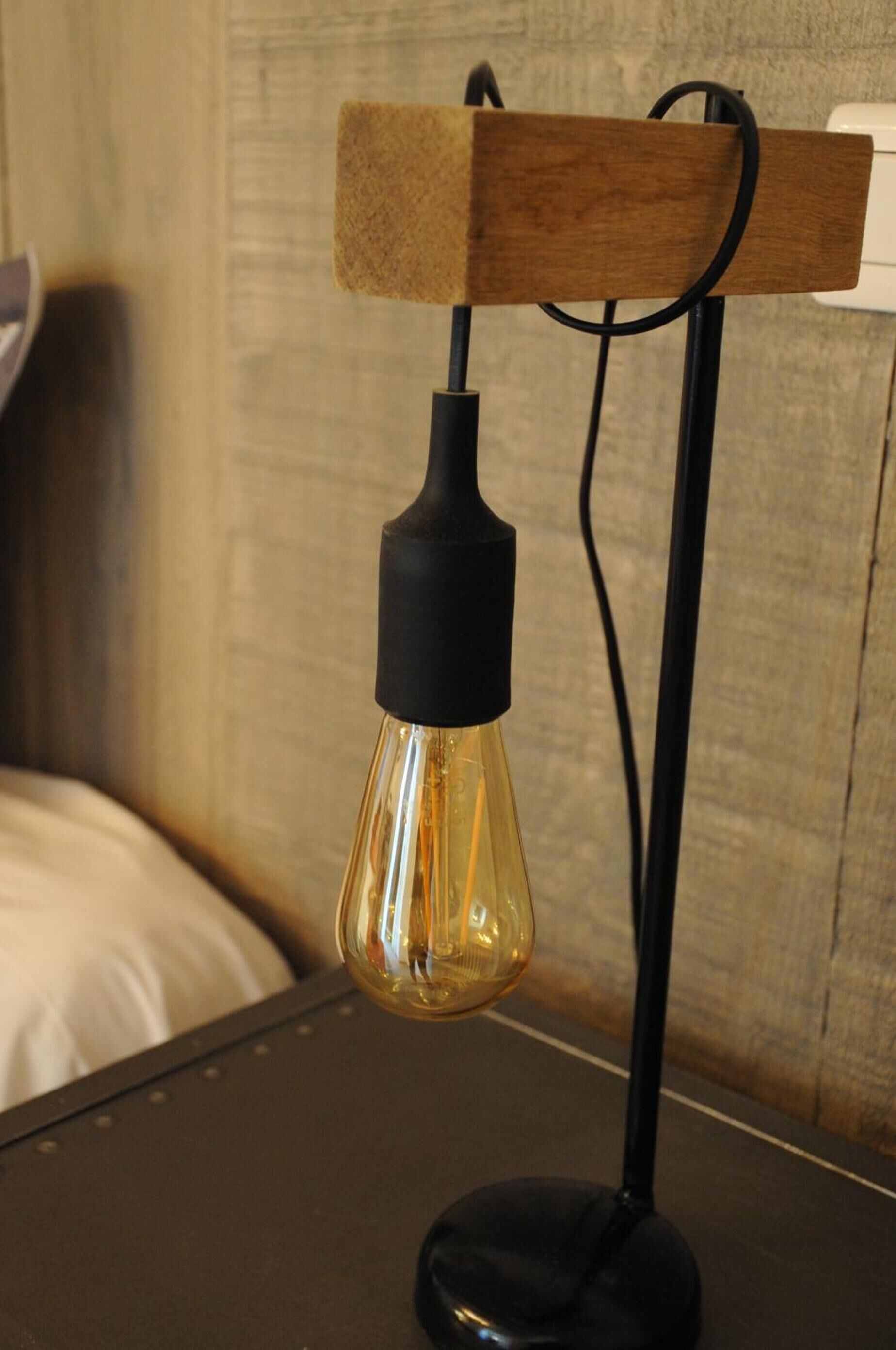 Une lampe de table moderne au design original, dotée d’une ampoule placée à l’intérieur d’un globe en verre et d’une structure de support en bois.
