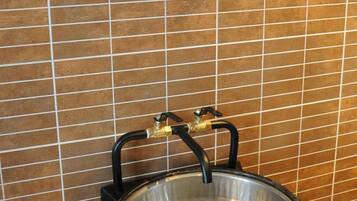 Een badkamer met een ronde spiegel en een roestvrijstalen wastafel op een betegelde muur.