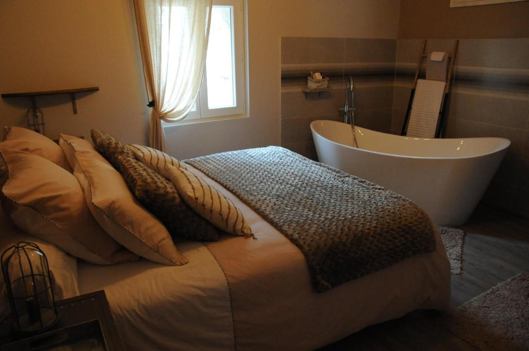 Een slaapkamer met een groot bed, een badkuip en een raam met gordijnen.