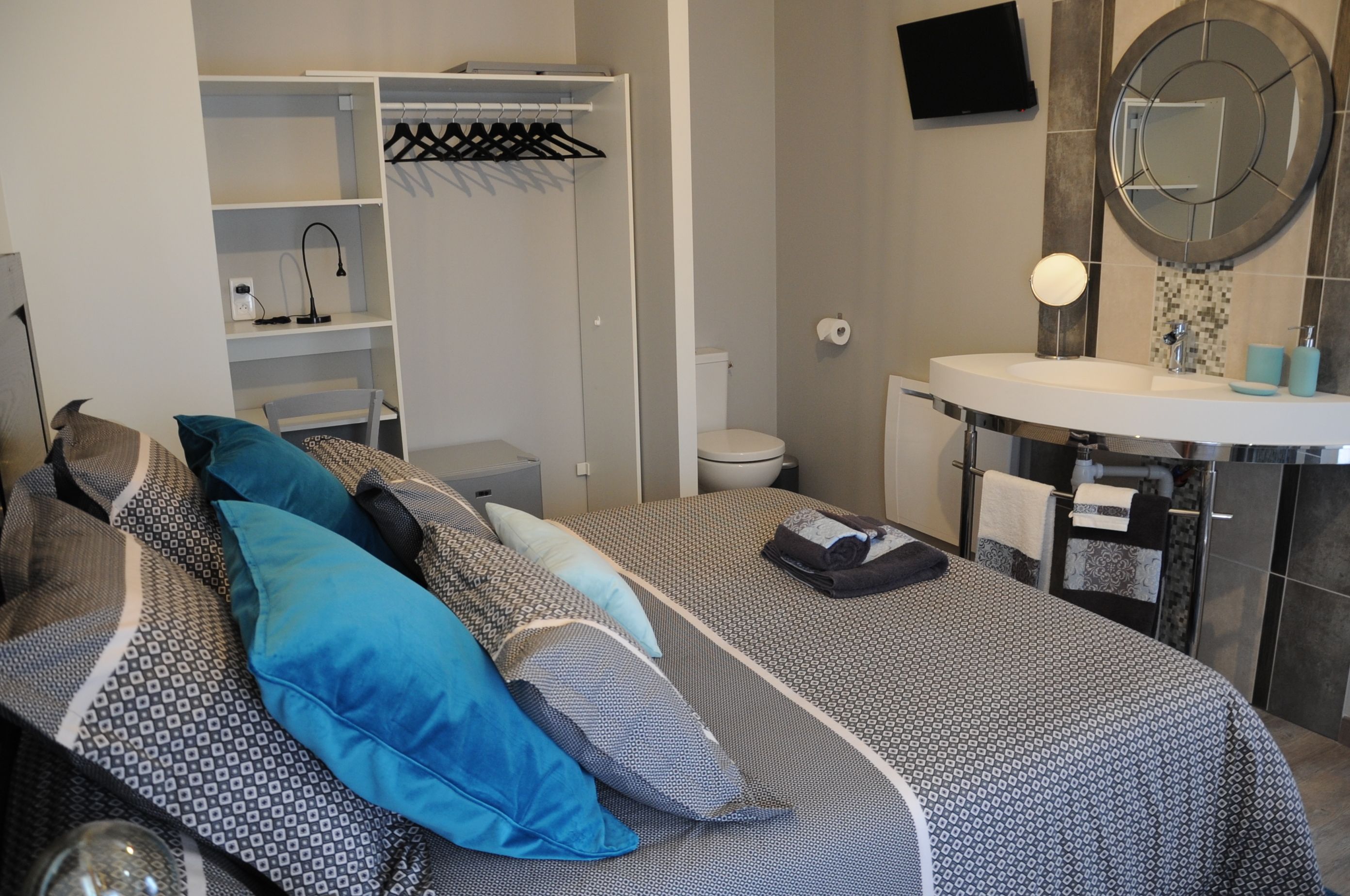 Una camera da letto con un letto, un comodino, un armadio, un bagno con lavandino e specchio, e un water.