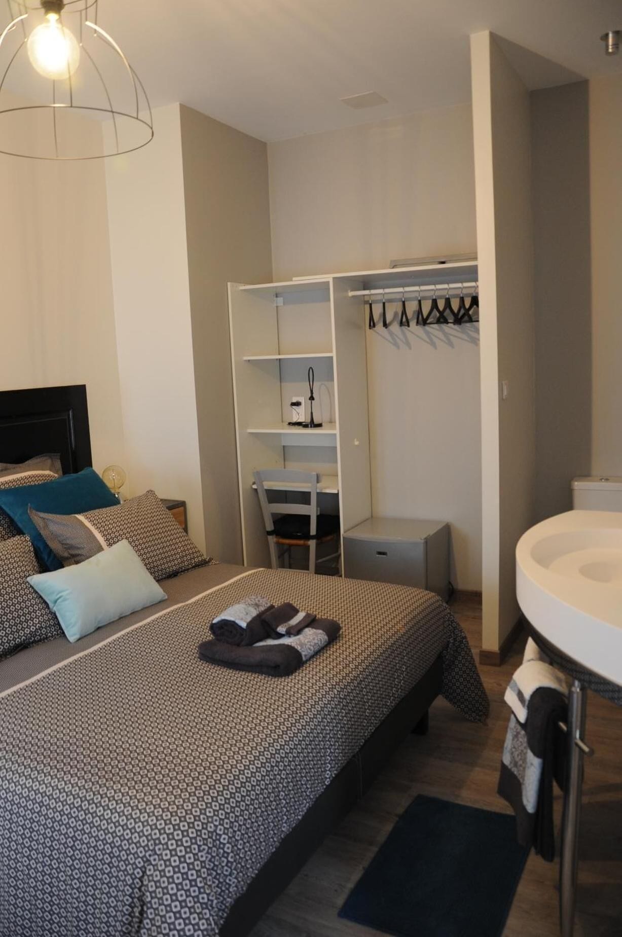 Un dormitorio con cama, escritorio, silla, armario y baño.