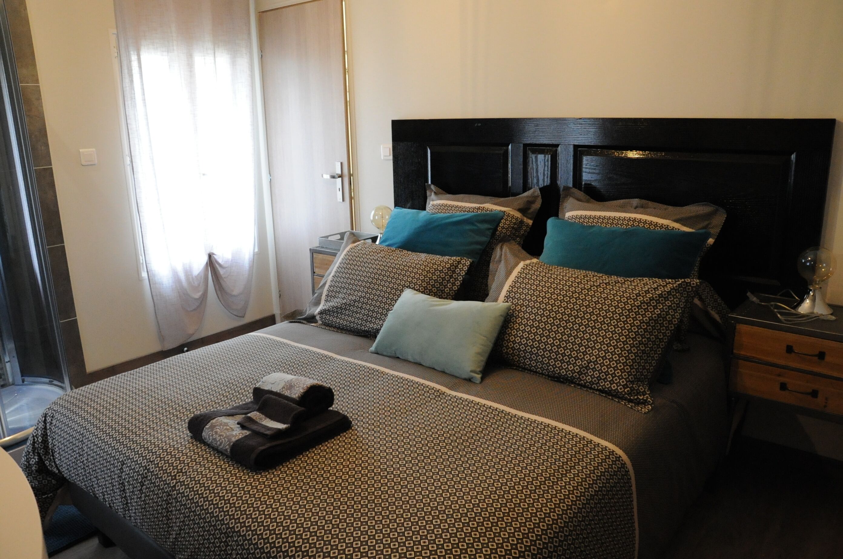 Une chambre d’hôtel avec un lit, une table de chevet, une lampe et une fenêtre avec des rideaux.