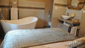 Un baño moderno con una bañera independiente, un tocador con espejo y un perchero para toallas.