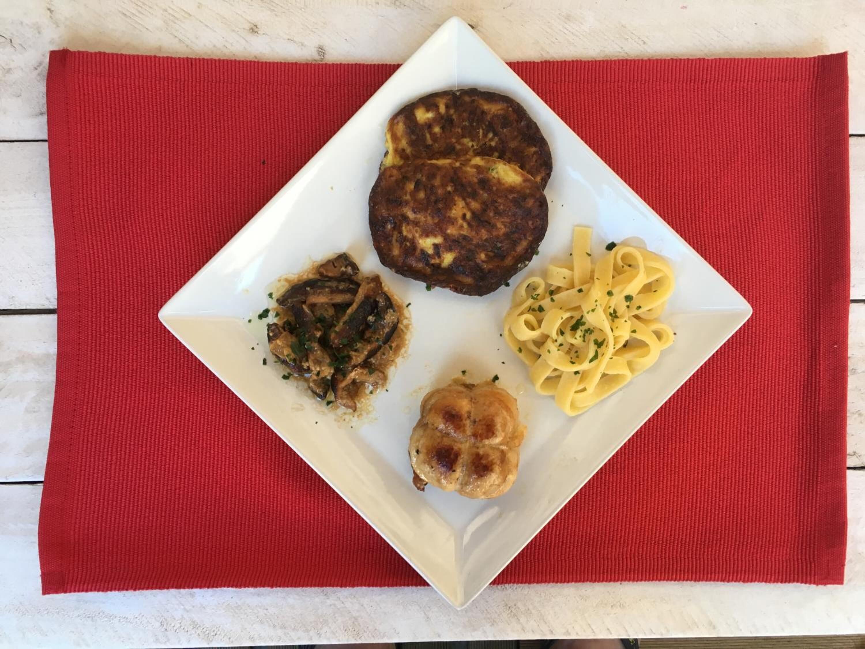 A white plate with food on a red placemat.