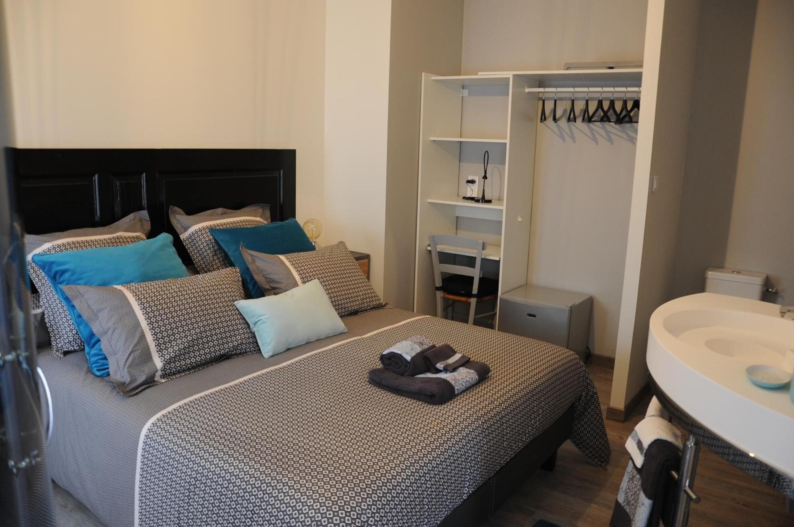 Un dormitorio con cama, armario, escritorio y baño.