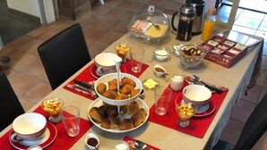 Mesa de desayuno con diversos alimentos, como croissants, frutas y salsas.