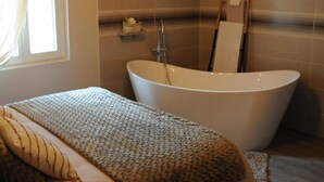 Un baño moderno con una bañera independiente, ducha y un ventanal que proporciona luz natural.
