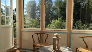 A room with a large window, two wooden chairs, a small table, and a lantern. - Lille Carlsson Studio (Broby)