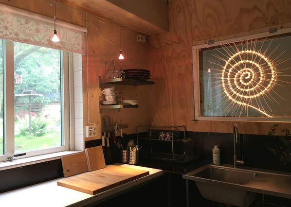A kitchen with wooden cabinets, a built-in bench, a sink, and a window with a decorative light fixture.