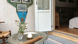 A room with a dining table, chairs, a vase with flowers, a white door, and a wall with framed pictures. - Lille Carlsson Studio (Broby)